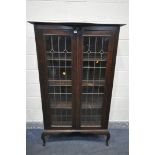 AN EARLY 20TH CENTURY ARTS AND CRAFTS TWO DOOR LEAD GLAZED BOOKCASE, with a shaped top, on