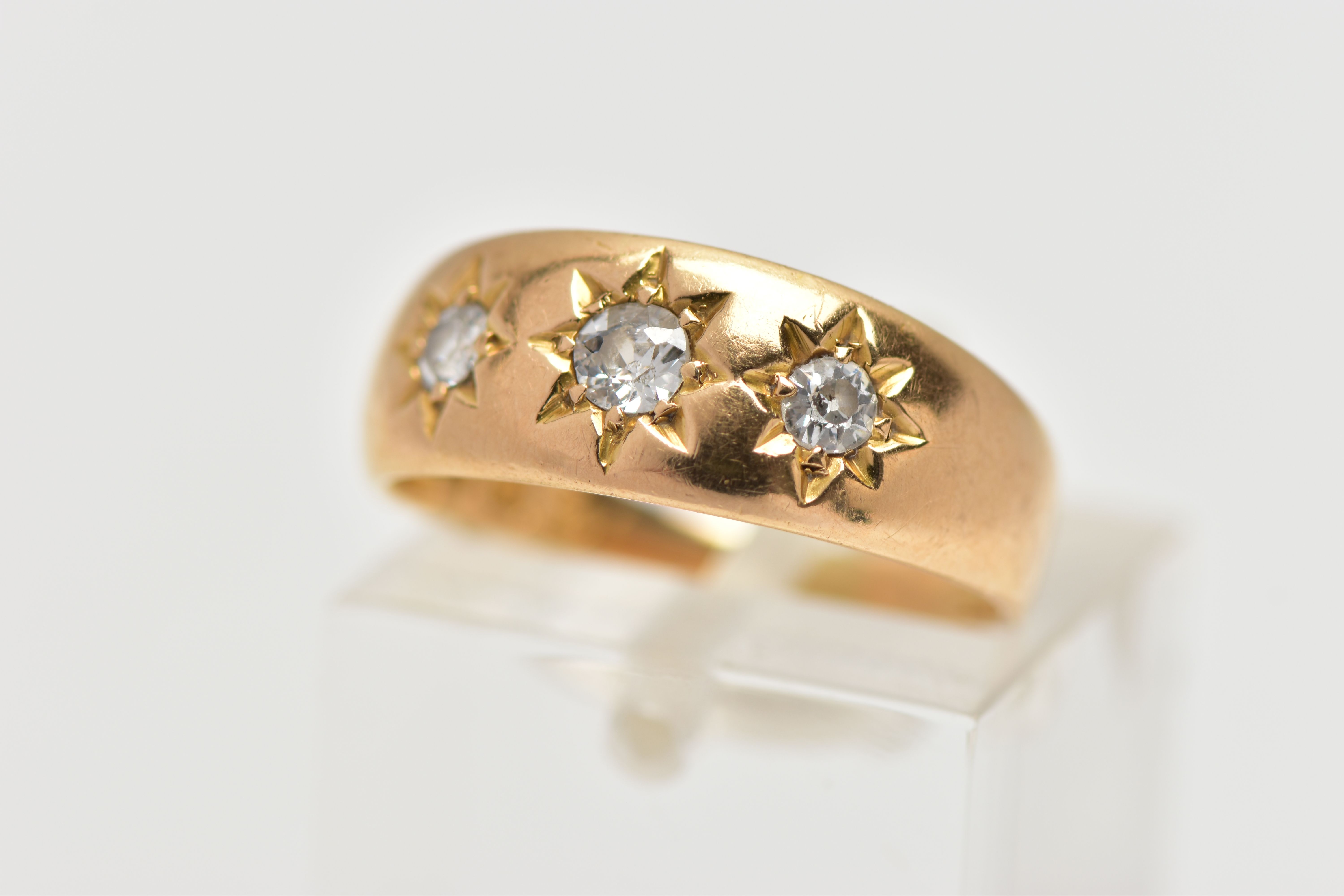 AN 18CT GOLD DIAMOND THREE STONE RING, the graduated old cut diamonds, within a star setting, to the