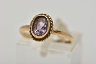A 9CT GOLD AMETHYST SINGLE STONE RING, the oval cut amethyst within a collet setting, to the rope