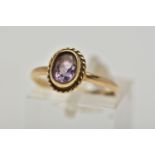 A 9CT GOLD AMETHYST SINGLE STONE RING, the oval cut amethyst within a collet setting, to the rope