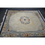 A LARGE RECTANGULAR CREAM GROUND CHINESE WOOLEN RUG, with foliate and geometric border and centre
