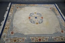 A LARGE RECTANGULAR CREAM GROUND CHINESE WOOLEN RUG, with foliate and geometric border and centre