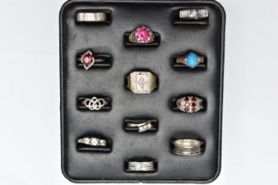 A SELECTION OF SILVER AND MAINLY WHITE METAL RINGS, sitting on a ring pad comprising twelve rings,