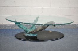 AN GLASS TOP OVAL COFFEE TABLE, the base in the form of an otter hunting a fish, length 140cm x