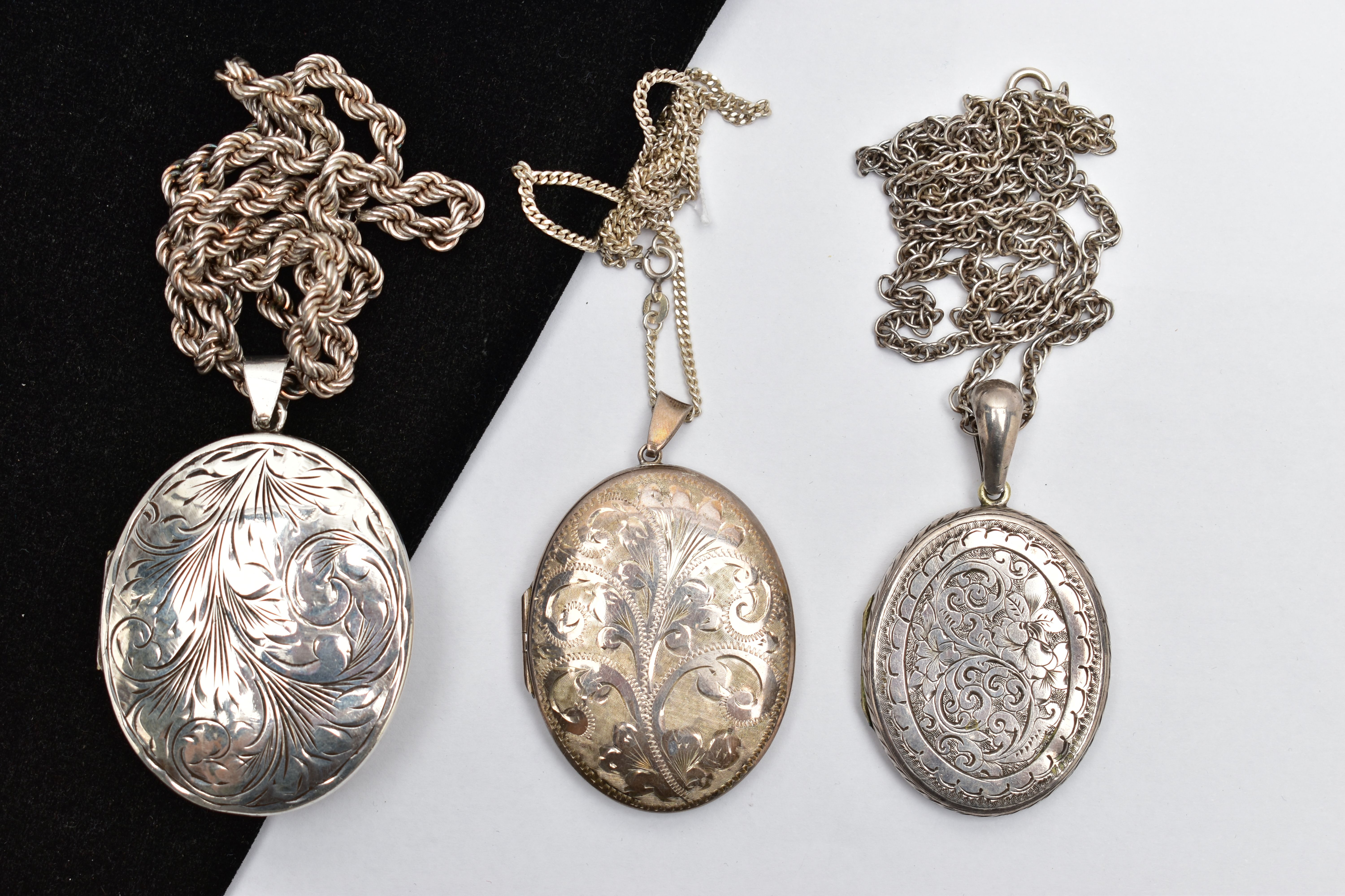 A SELECTION OF SILVER AND WHITE METAL LOCKETS, WITH CHAINS, the first a silver embossed oval locket,