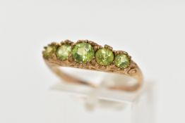 A 9CT GOLD FIVE STONE PERIDOT RING, designed with five graduated circular cut peridots, scrolling