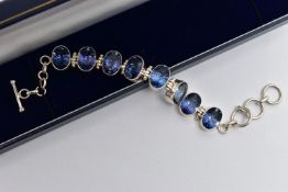 A SILVER IOLITE BRACELET, the oval cut iolites collet set, with hinged spacers, to the circular link