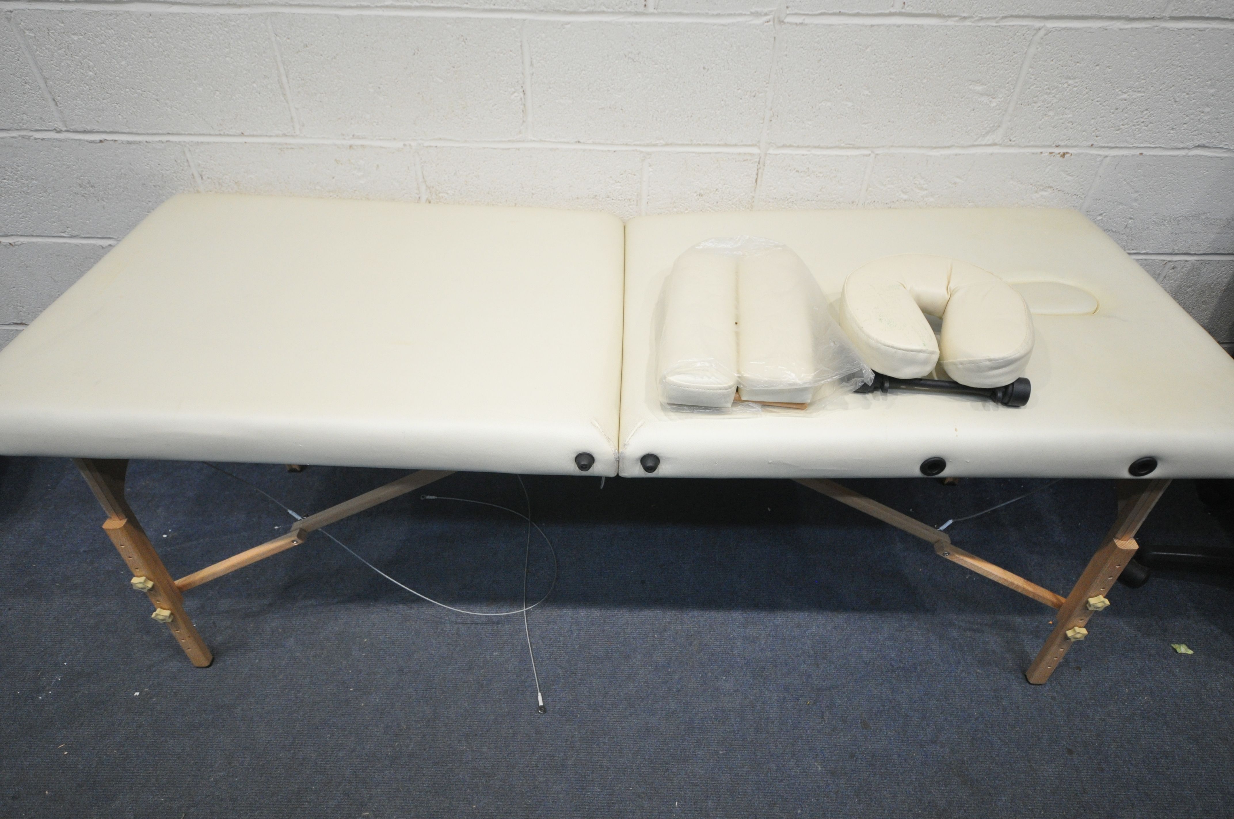 A CREAM LEATHERETTE FOLDING MASSAGE TABLE, with head and footrests (some stains, and a carry bag,