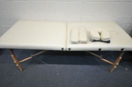 A CREAM LEATHERETTE FOLDING MASSAGE TABLE, with head and footrests (some stains, and a carry bag,