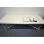 A CREAM LEATHERETTE FOLDING MASSAGE TABLE, with head and footrests (some stains, and a carry bag,