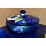A BOXED MOORCROFT POTTERY 'BLUE PANSY' COVERED BOWL, of shallow squat form, having tube lined blue
