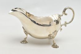 A GEORGE V SILVER SAUCEBOAT, wavy rim, 'C' scroll handle, on three cabriole legs with shell knees