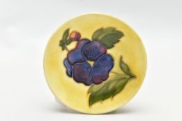 A MOORCROFT POTTERY COASTER DECORATED WITH A PANSY ON A PALE YELLOW GROUND, impressed marks, bears