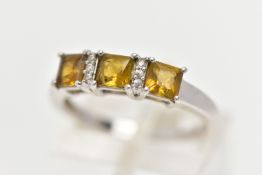 A 9CT WHITE GOLD GEM SET RING, designed with a row of three square yellowish/green stones assessed