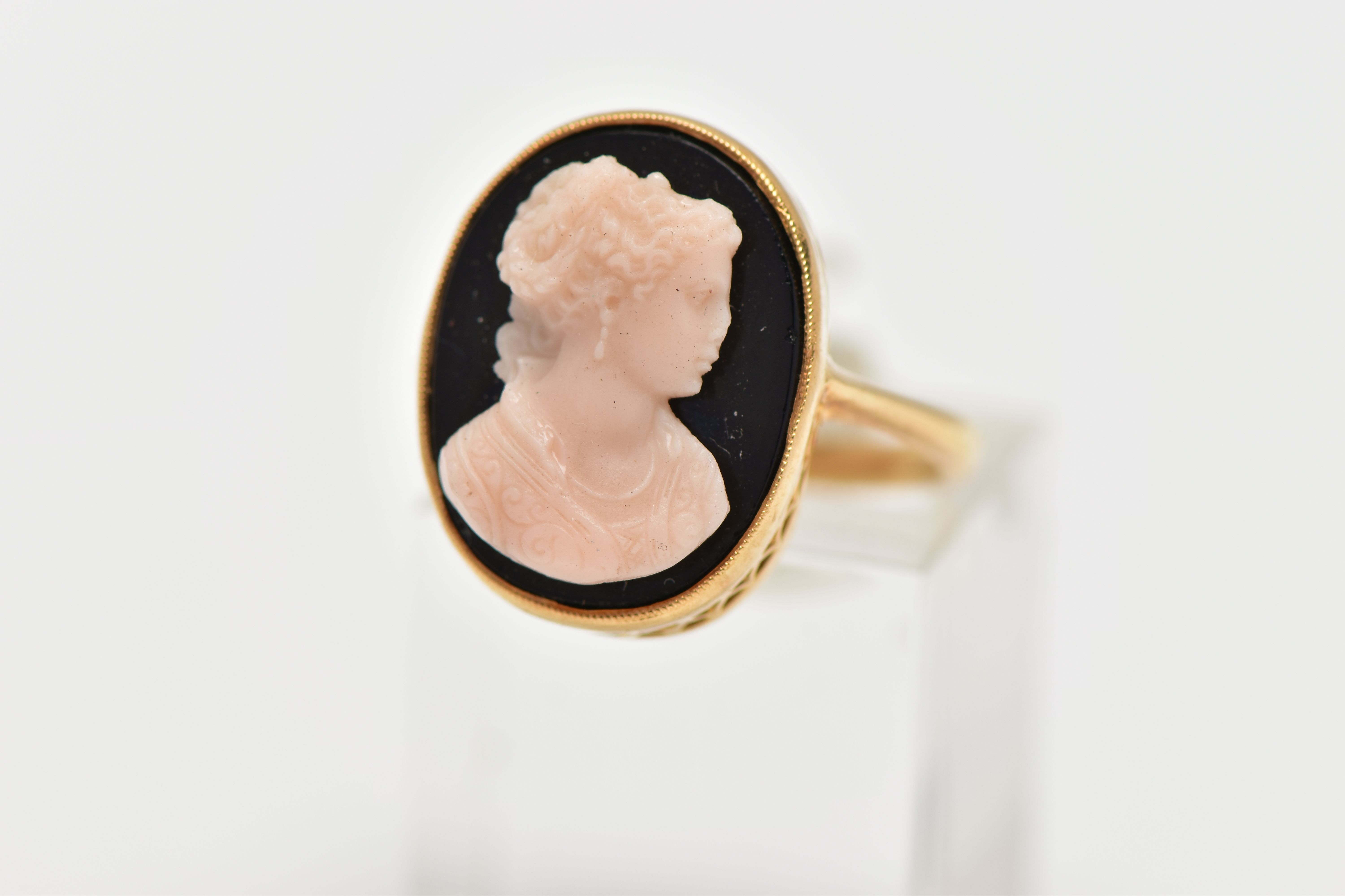 A YELLOW METAL CAMEO RING, oval onyx panel set with a raised cameo of a lady in profile, milgrain