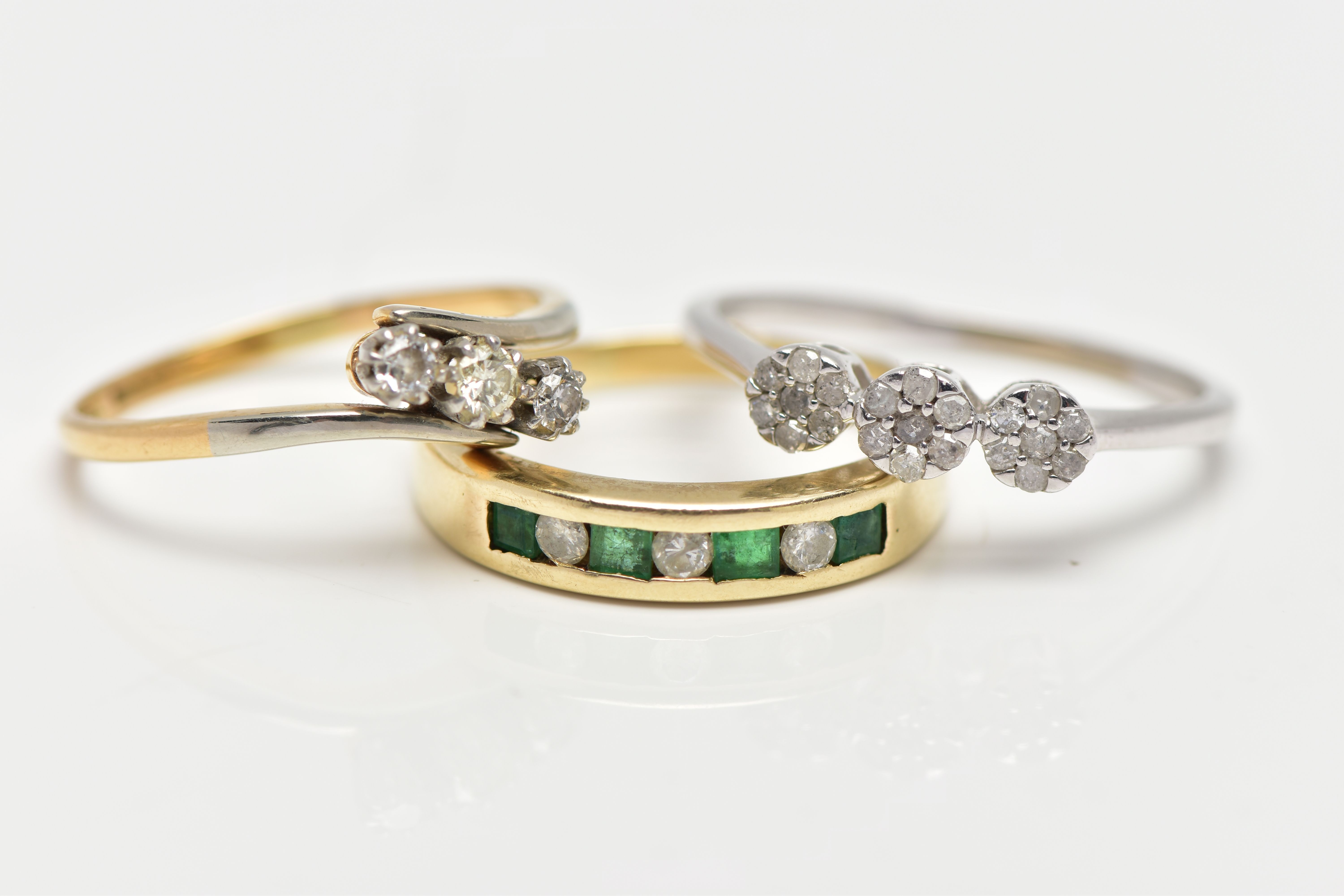 THREE GEM SET RINGS, the first a yellow metal half eternity ring set with four square cut emeralds