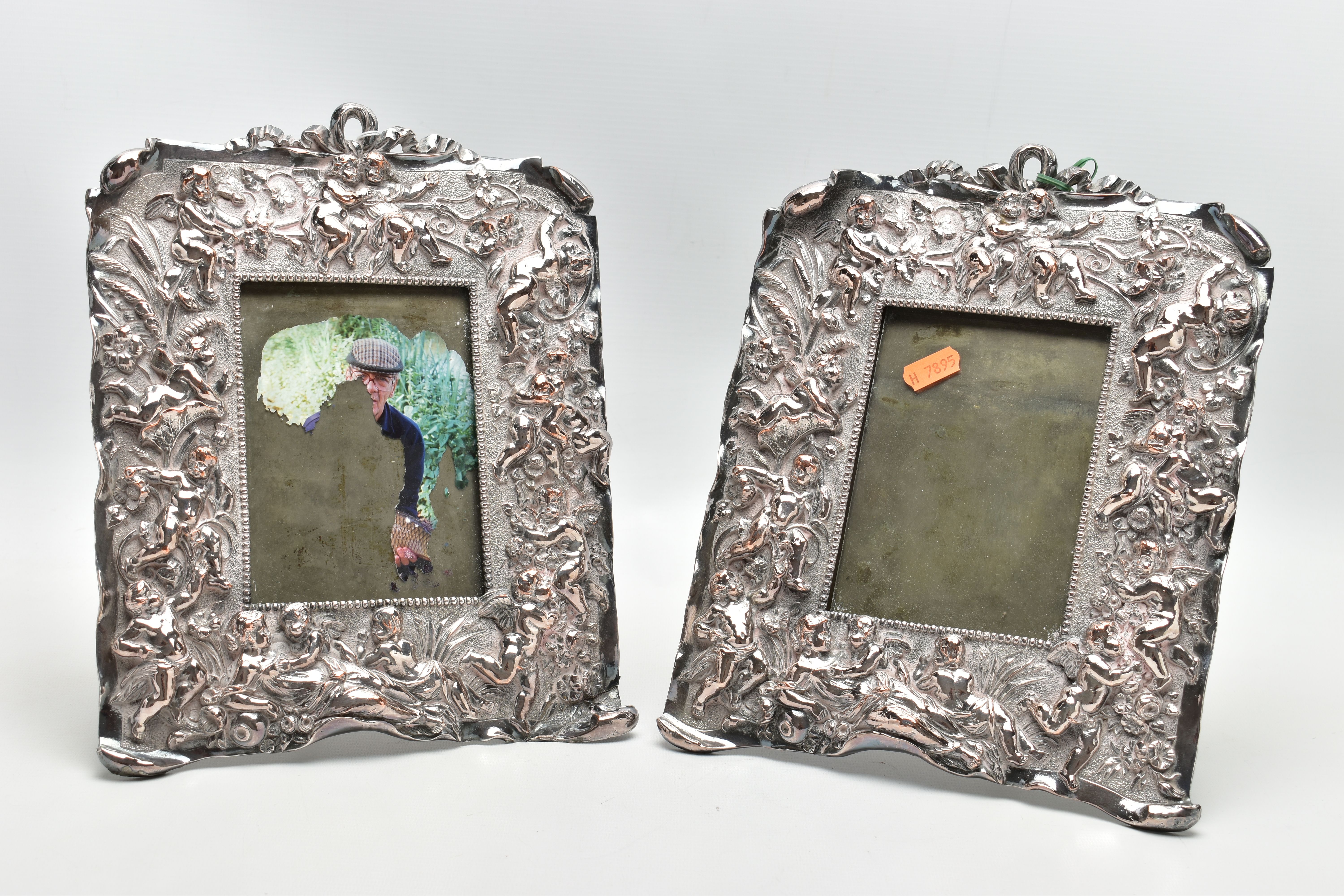 A PAIR OF WHITE METAL PHOTO FRAMES, rectangular form, detailed with a number of cherubs, a woman and