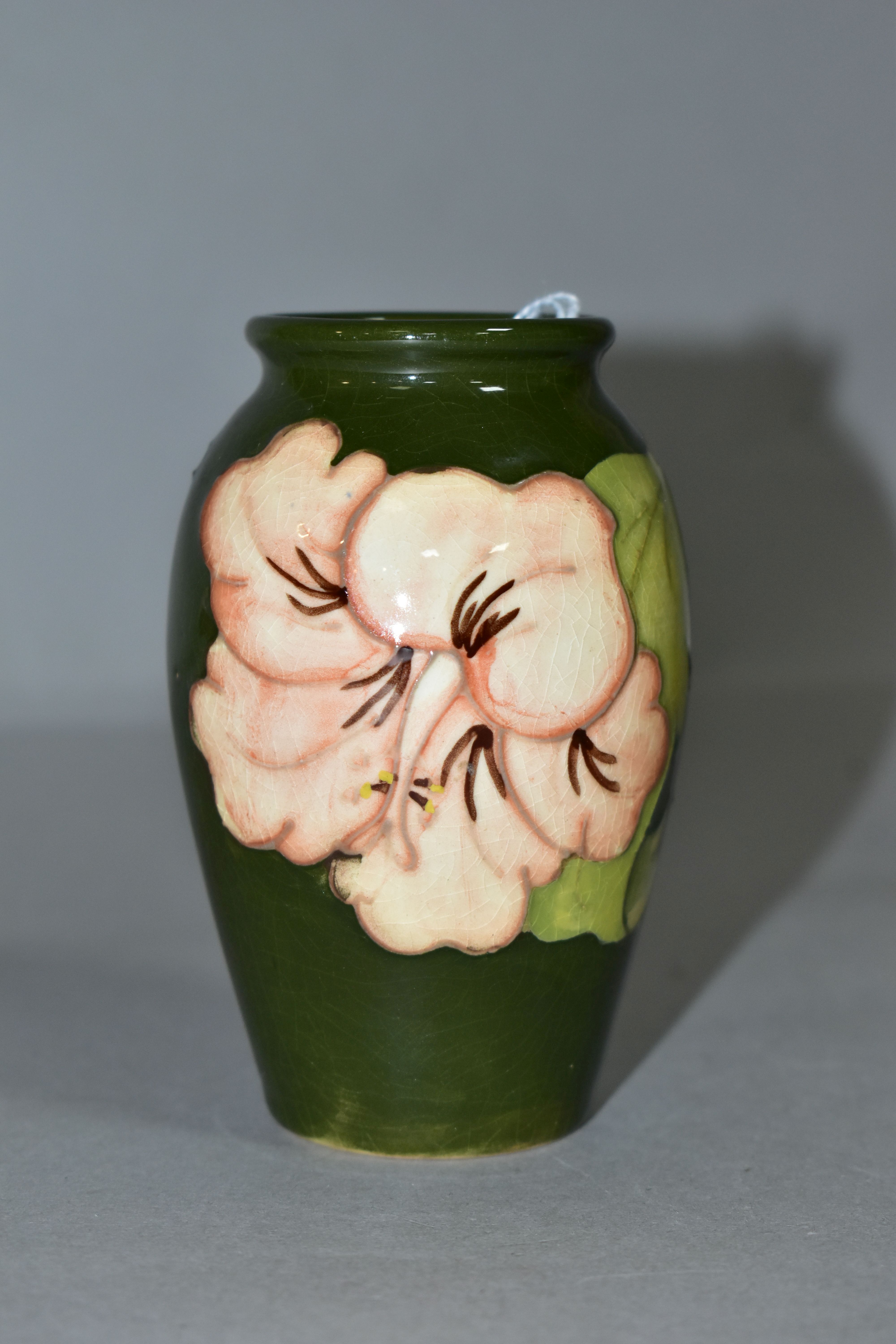 A MOORCROFT POTTERY BALUSTER SHAPED BUD VASE DECORATED WITH CORAL HIBISCUS ON A GREEN GROUND,