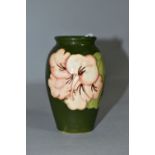 A MOORCROFT POTTERY BALUSTER SHAPED BUD VASE DECORATED WITH CORAL HIBISCUS ON A GREEN GROUND,