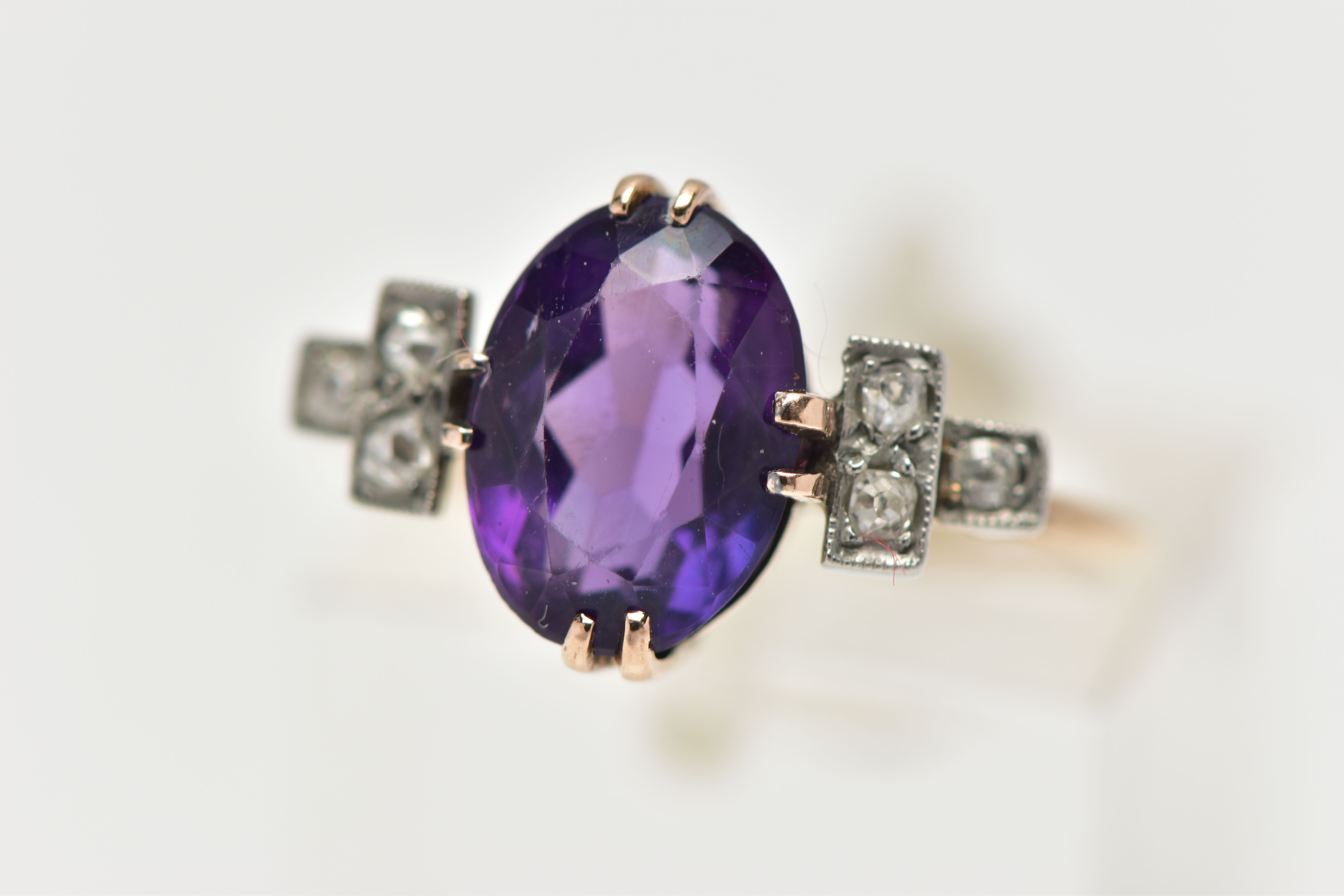 AN EARLY 20TH CENTURY DRESS RING, an oval cut deep purple amethyst, prong set in yellow gold,