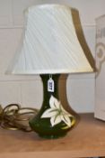 A MOORCROFT POTTERY TABLE LAMP DECORATED WITH WHITE BERMUDA LILY PATTERN ON A GREEN GROUND, the lamp