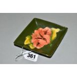 A MOORCROFT POTTERY LOZENGE SHAPED PIN DISH DECORATED WITH A CORAL HIBISCUS ON A GREEN GROUND,