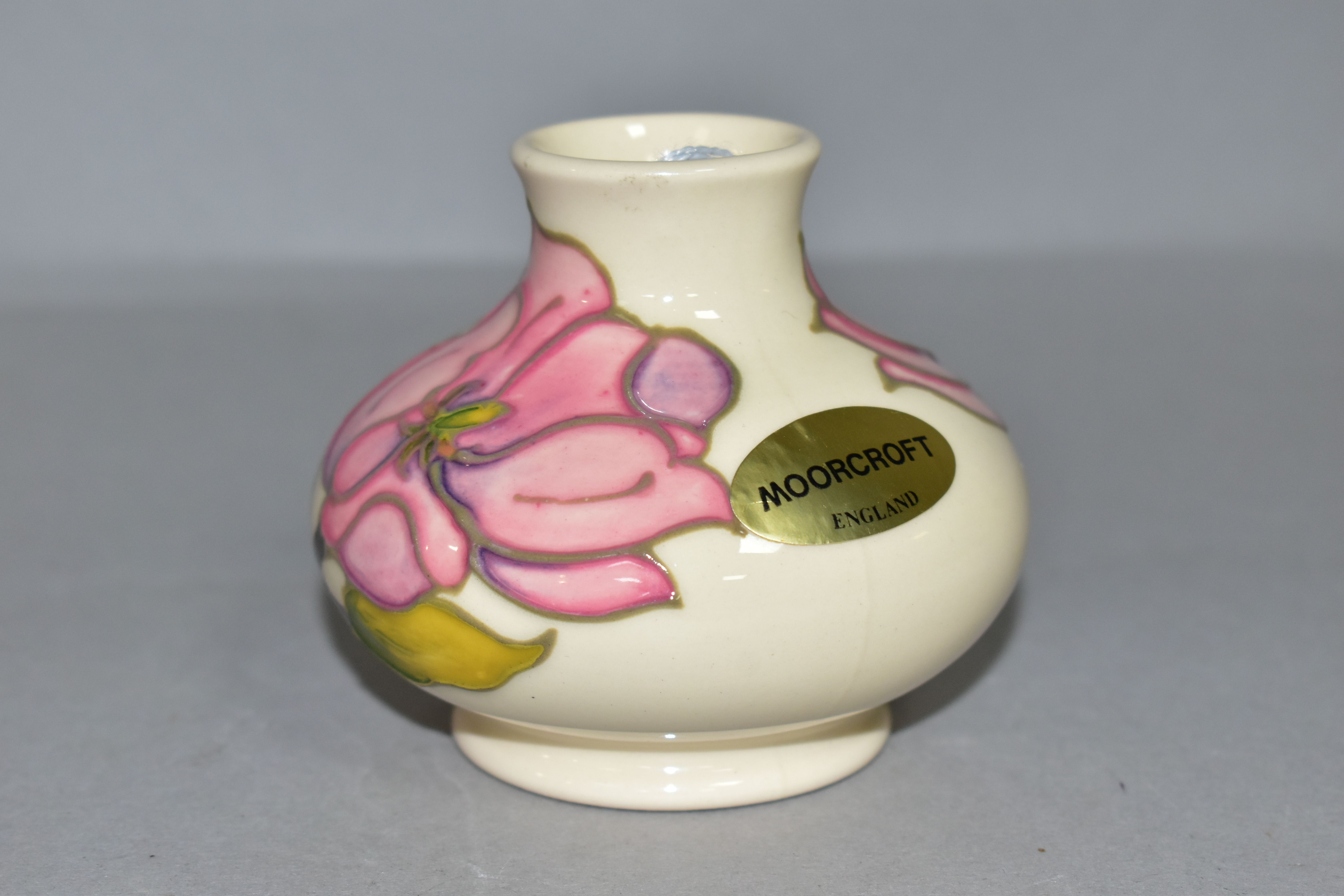 A MOORCROFT POTTERY SQUAT BALUSTER VASE DECORATED WITH PINK MAGNOLIA ON A CREAM GROUND, bears gilt