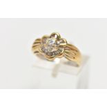 A MODERN YELLOW METAL DIAMOND CLUSTER RING, set with a principal round brilliant cut diamond, within