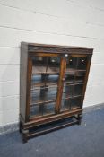 AN EARLY 20th CENTURY OAK GLAZED BOOKCASE with three adjustable shelves, turned legs and mirrored