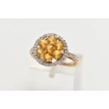 A 9CT GOLD YELLOW SAPPHIRE AND DIAMOND CLUSTER RING, the openwork circular cut yellow sapphire