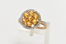 A 9CT GOLD YELLOW SAPPHIRE AND DIAMOND CLUSTER RING, the openwork circular cut yellow sapphire