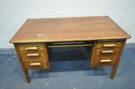 A MID CENTURY OAK DESK with three graduated drawers, opposite two drawers and brushing slide (no