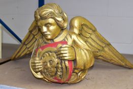 A CARVED WOODEN ANGEL, painted gold holding a red shield decorated with a golden lion head, width