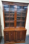 A 20TH CENTURY MAHOGANY BOOKCASE, the top enclosing two divisions, above paneled cupboard doors,