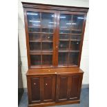 A 20TH CENTURY MAHOGANY BOOKCASE, the top enclosing two divisions, above paneled cupboard doors,