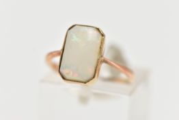 A YELLOW METAL OPAL RING, rectangular cut opal cabochon with cut off corners, milgrain collet mount,