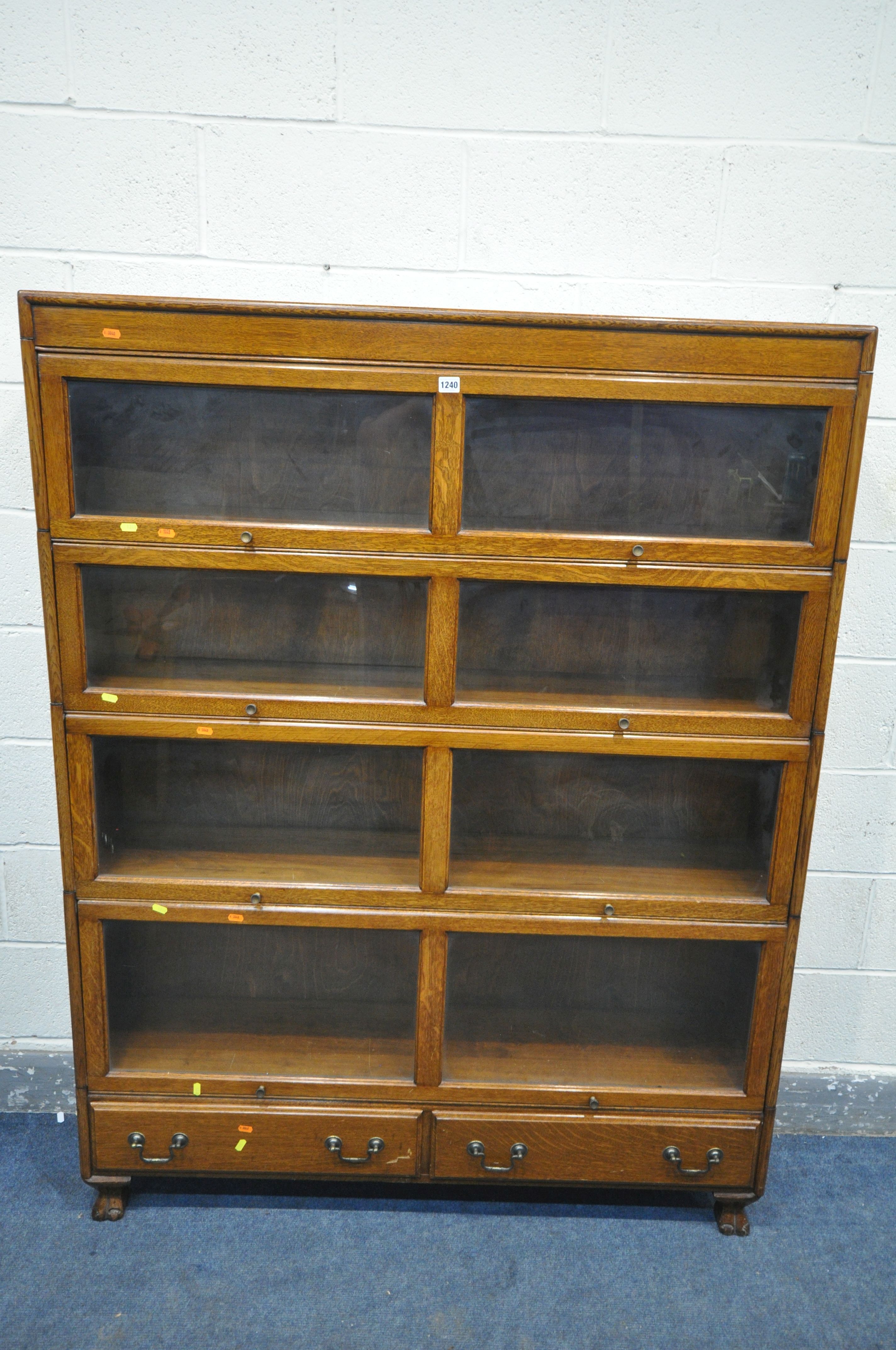 AN EARLY 20TH CENTURY OAK FOUR SECTION BOOKCASE, with twin glazed hide and fall doors, over a base