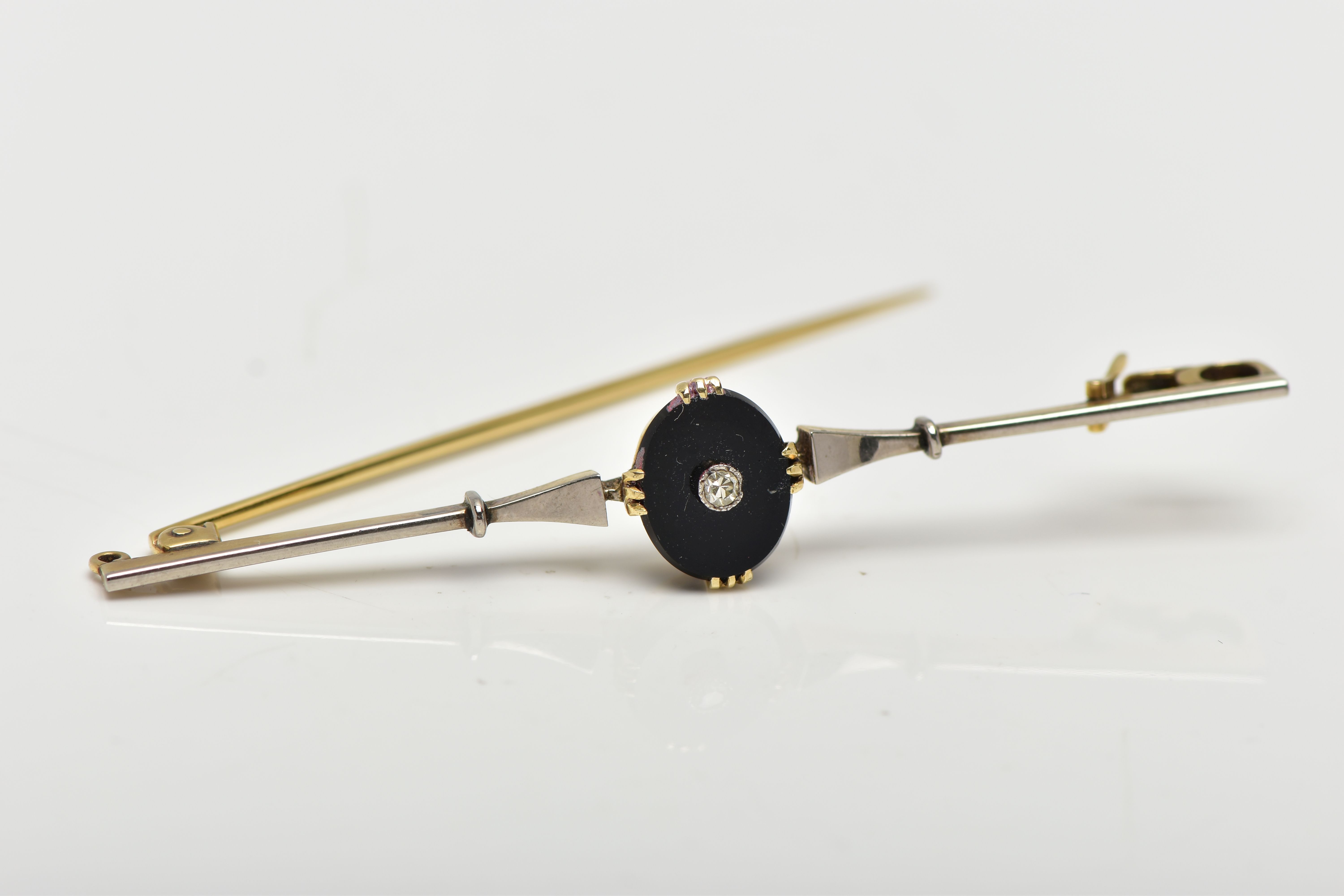 A YELLLOW METAL DIAMOND SET BAR BROOCH, centring on an oval onyx panel set with a single cut diamond