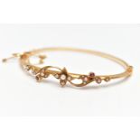 AN EARLY 20TH CENTURY 15CT GOLD BANGLE, a hinged bangle, decorated with a floral design, set with
