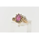 A 9CT GOLD RUBY AND DIAMOND RING, centring on an oval cut ruby, in a four claw setting, with