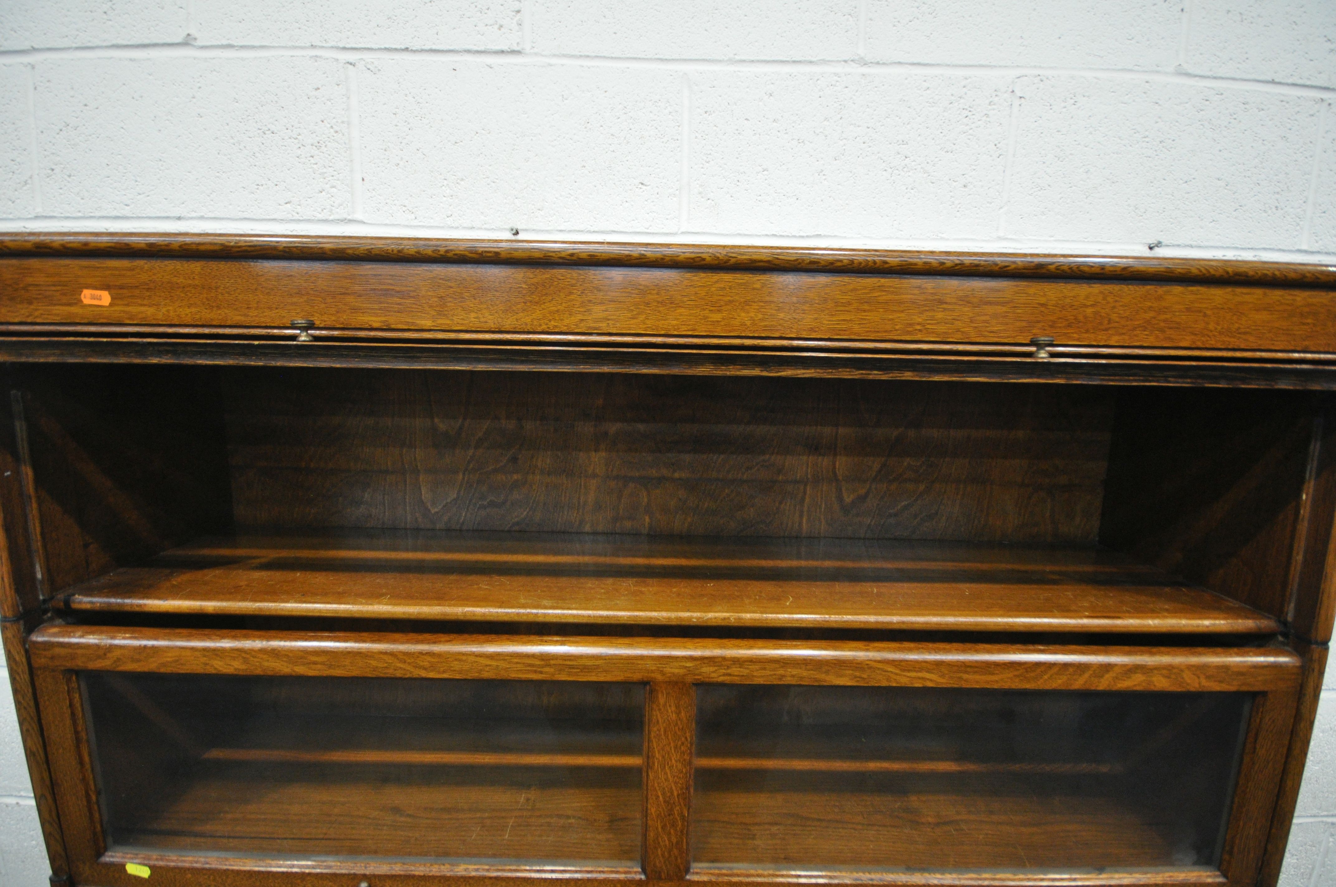 AN EARLY 20TH CENTURY OAK FOUR SECTION BOOKCASE, with twin glazed hide and fall doors, over a base - Image 2 of 3