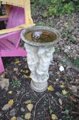 A COMPOSITE BIRD BATH in the form of three winged cherubs standing on a column holding the bowl