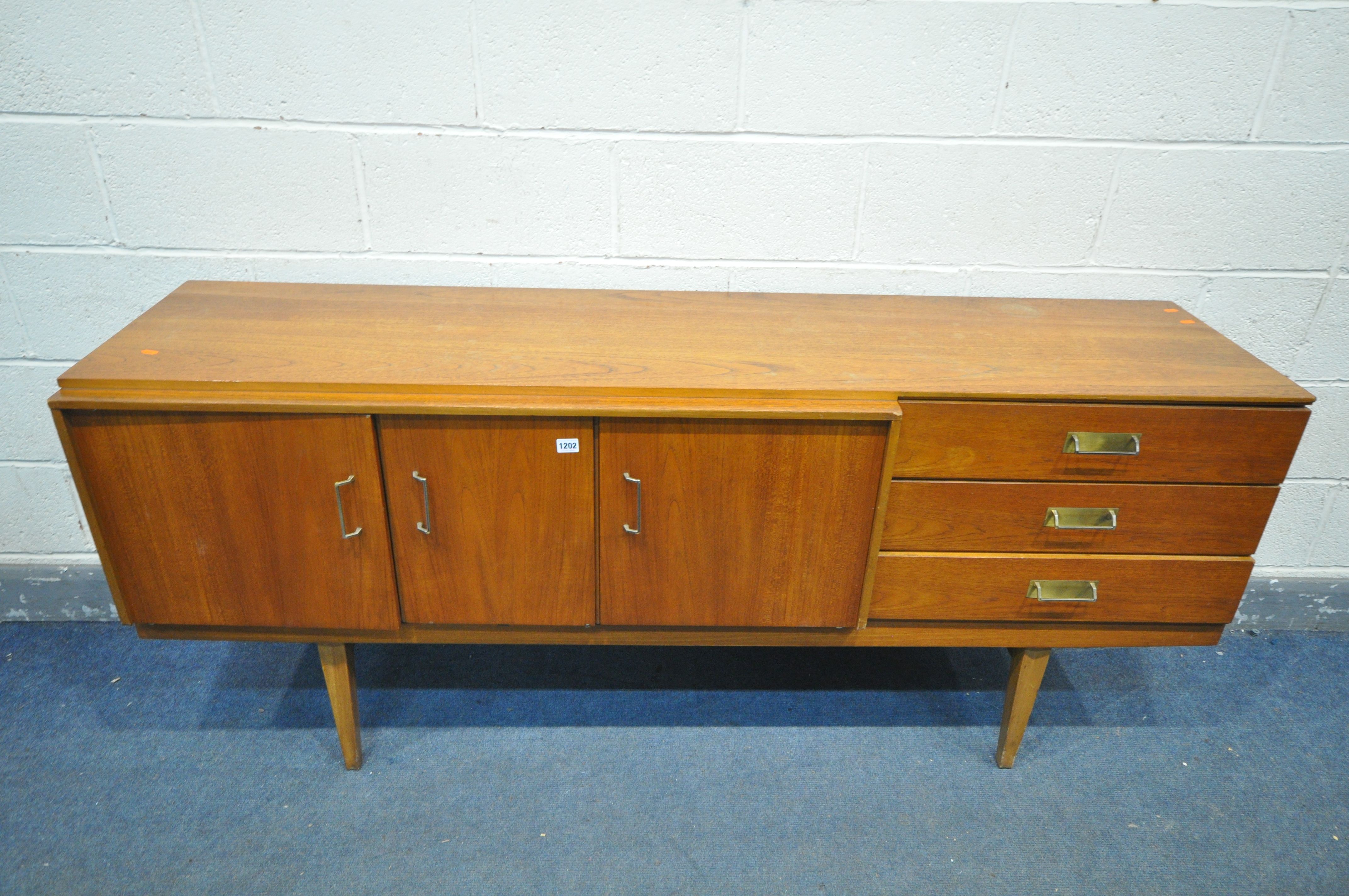 A MID CENTURY TEAK BEAUTILITY SIDEBOARD, with three drawers, two cupboard doors, flanking a pull out