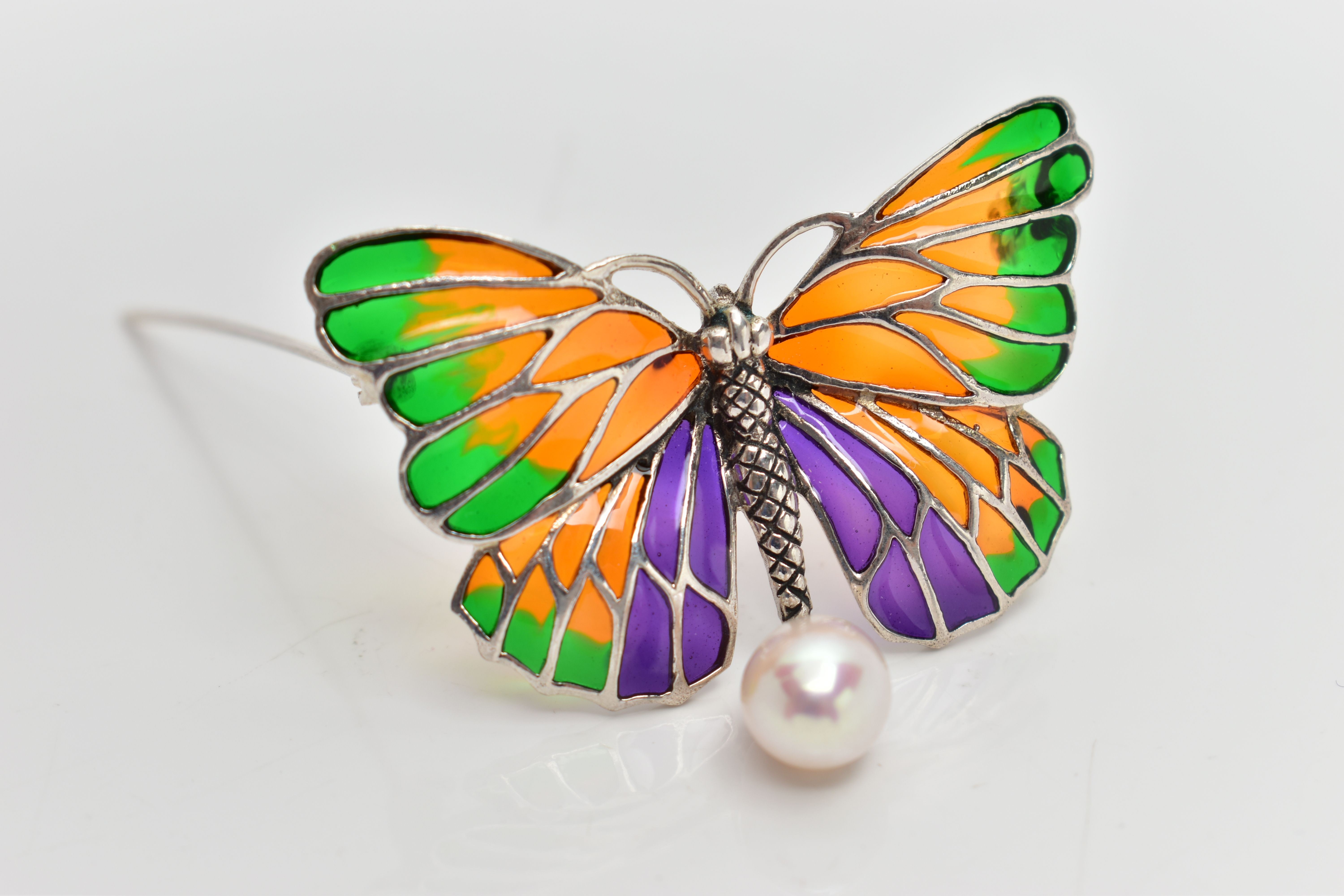 A PLIQUE A JOUR BROOCH, designed as a white metal butterfly, displaying green, orange and purple