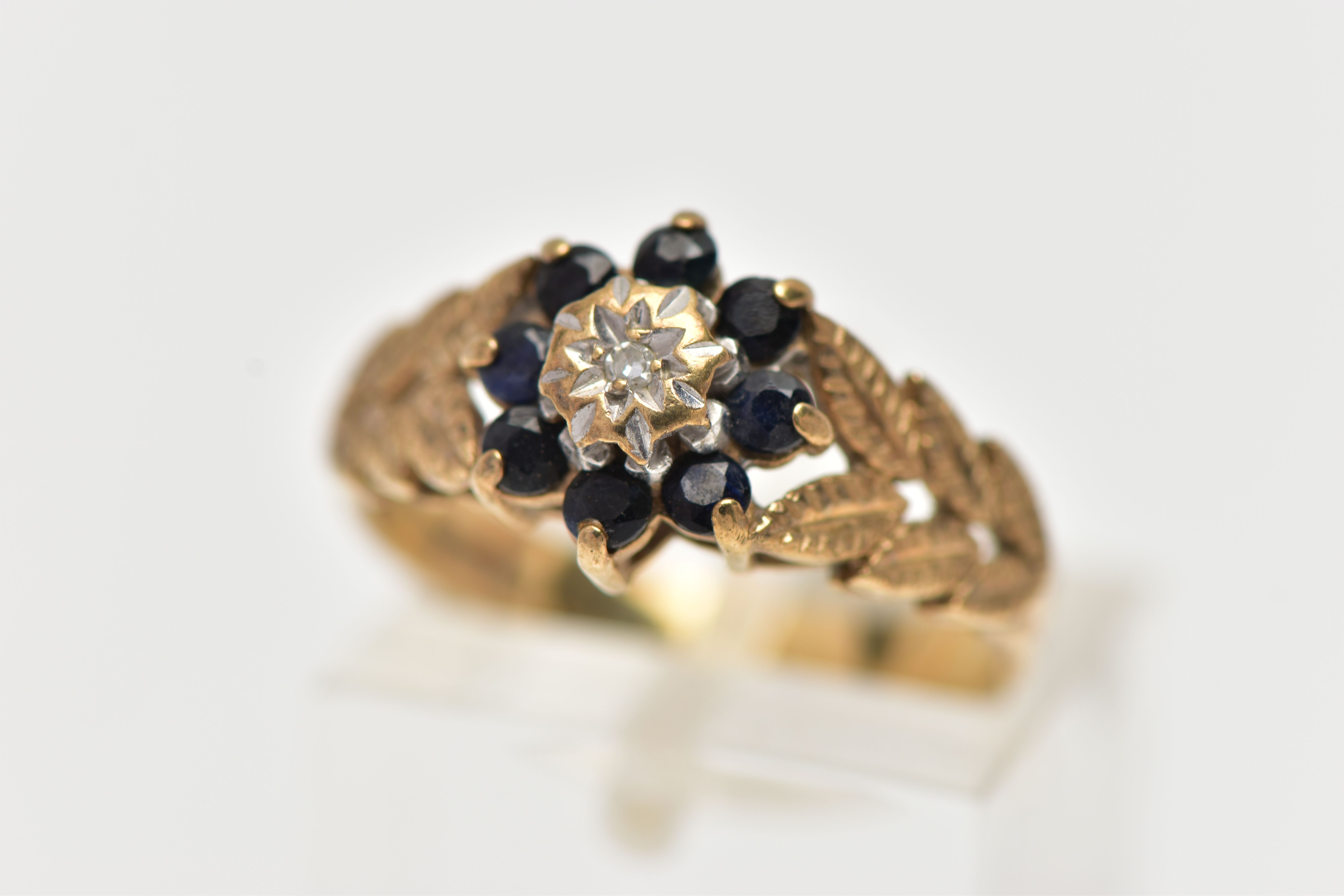 A 9CT GOLD DIAMOND AND SAPPHIRE CLUSTER RING, the illusion set single cut diamond, within a circular