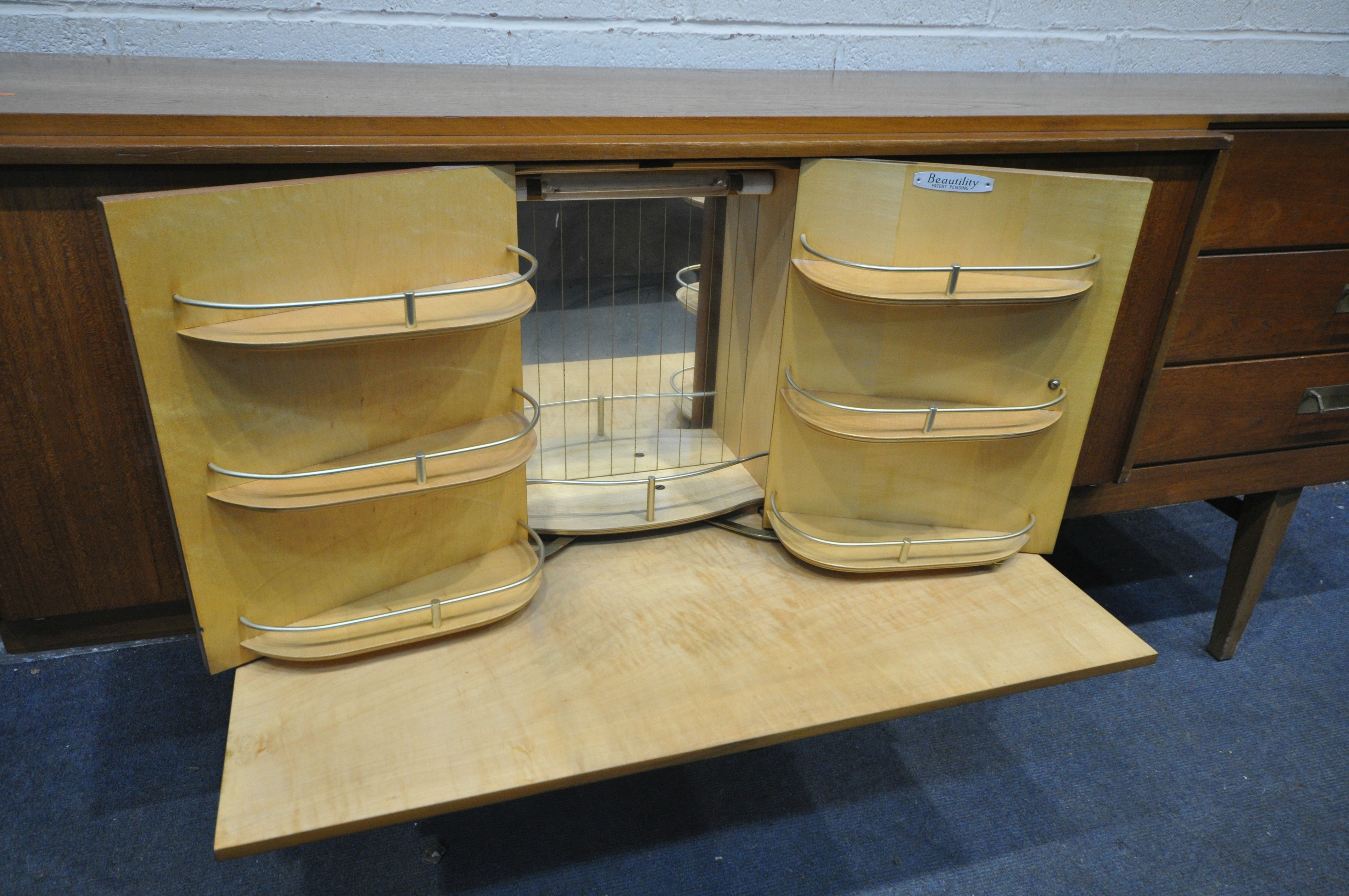 A MID CENTURY TEAK BEAUTILITY SIDEBOARD, with three drawers, two cupboard doors, flanking a pull out - Image 3 of 3