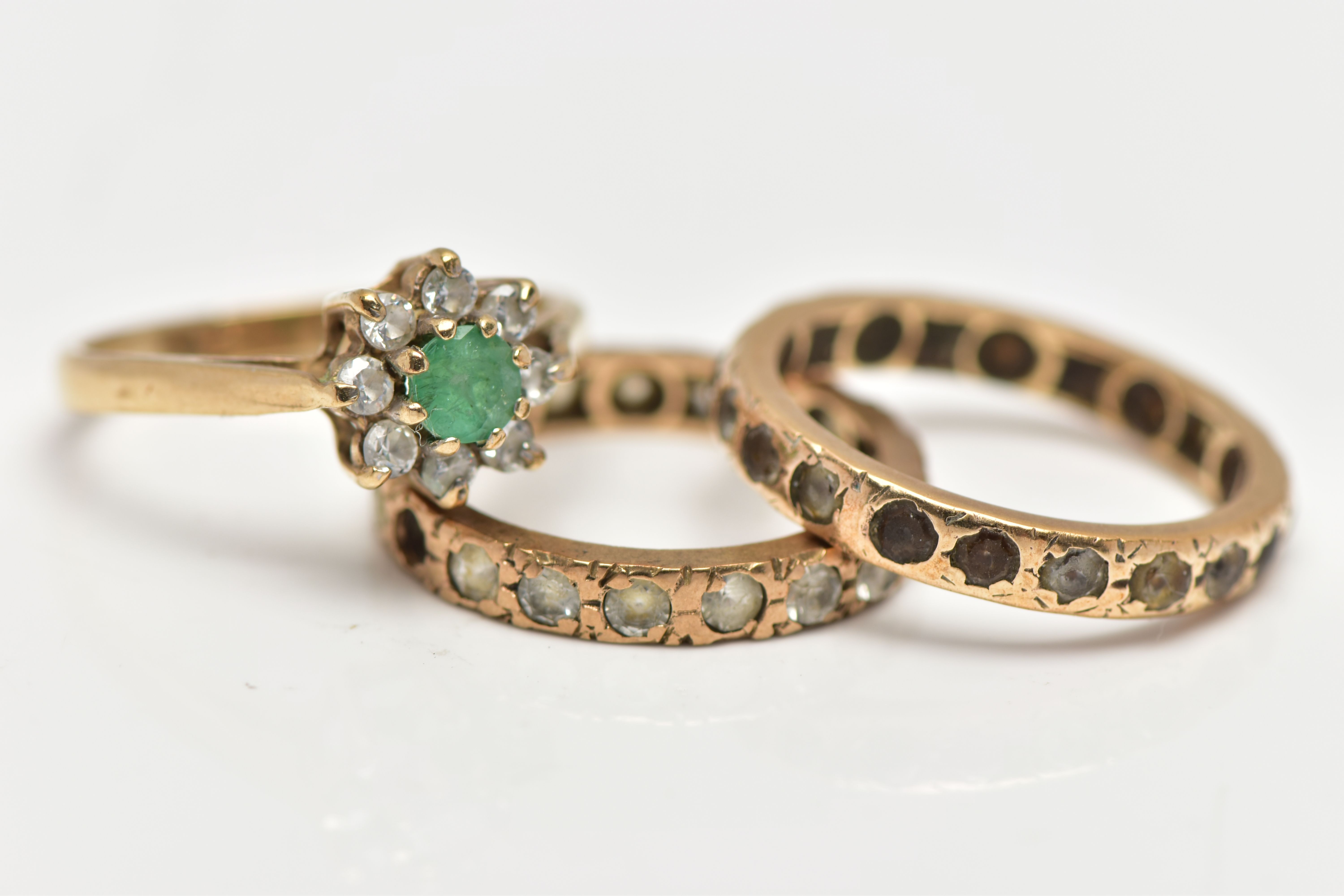 THREE GEM SET RINGS, the first a 9ct gold cluster ring set with a circular cut emerald within a