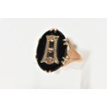 A YELLOW METAL INITIAL RING, an oval cut onyx centrally set with a yellow metal letter, prong set in