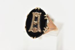 A YELLOW METAL INITIAL RING, an oval cut onyx centrally set with a yellow metal letter, prong set in