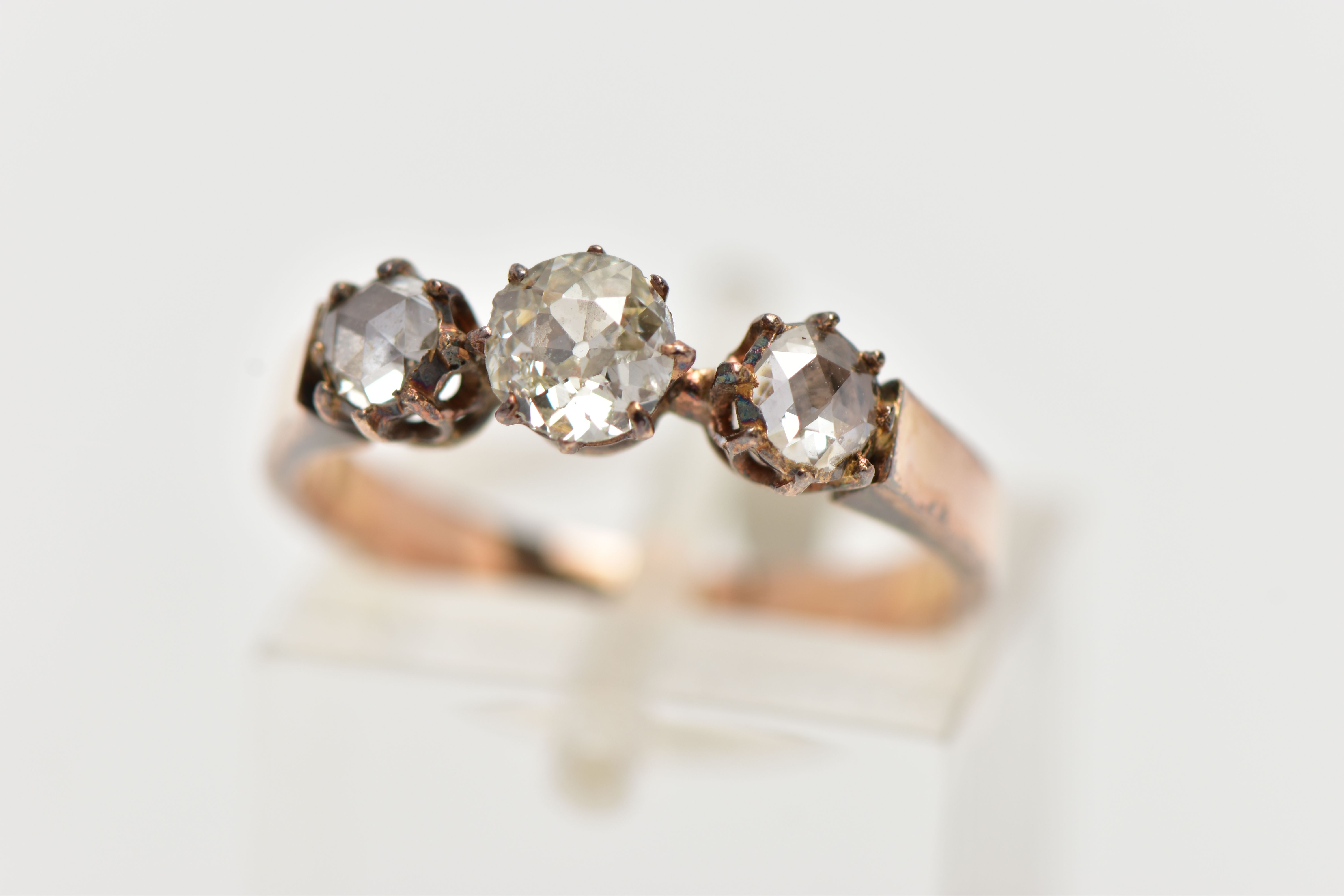 A YELLOW METAL DIAMOND RING, centering on an old cut diamond, and two rose cut diamonds, prong set